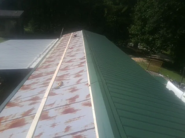 Old rusted panels beside newly installed green metal roofing — Wind Damage Roof Repair by Roofing Brothers in Mound