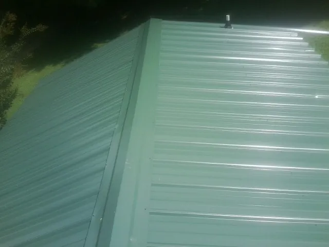 New green metal panels meeting at the ridge of a roof — Flat Roof Repair work by our crew in Mound