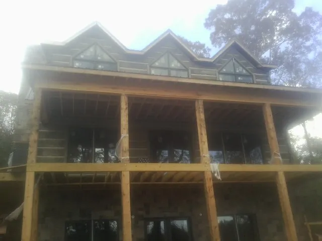 Dormers and porch framing on a large log home under construction — Roof Coating work by our crew in Mound