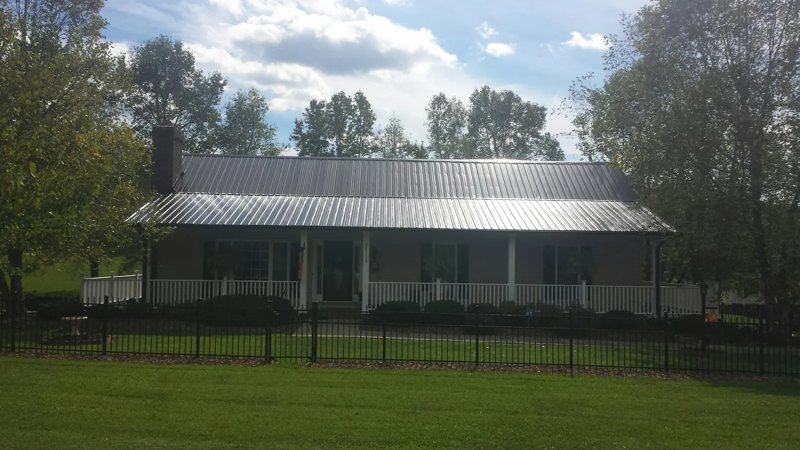 Gray metal roof on a brick ranch with a full width front porch — Gutter Guard Installation work by our crew in Mound