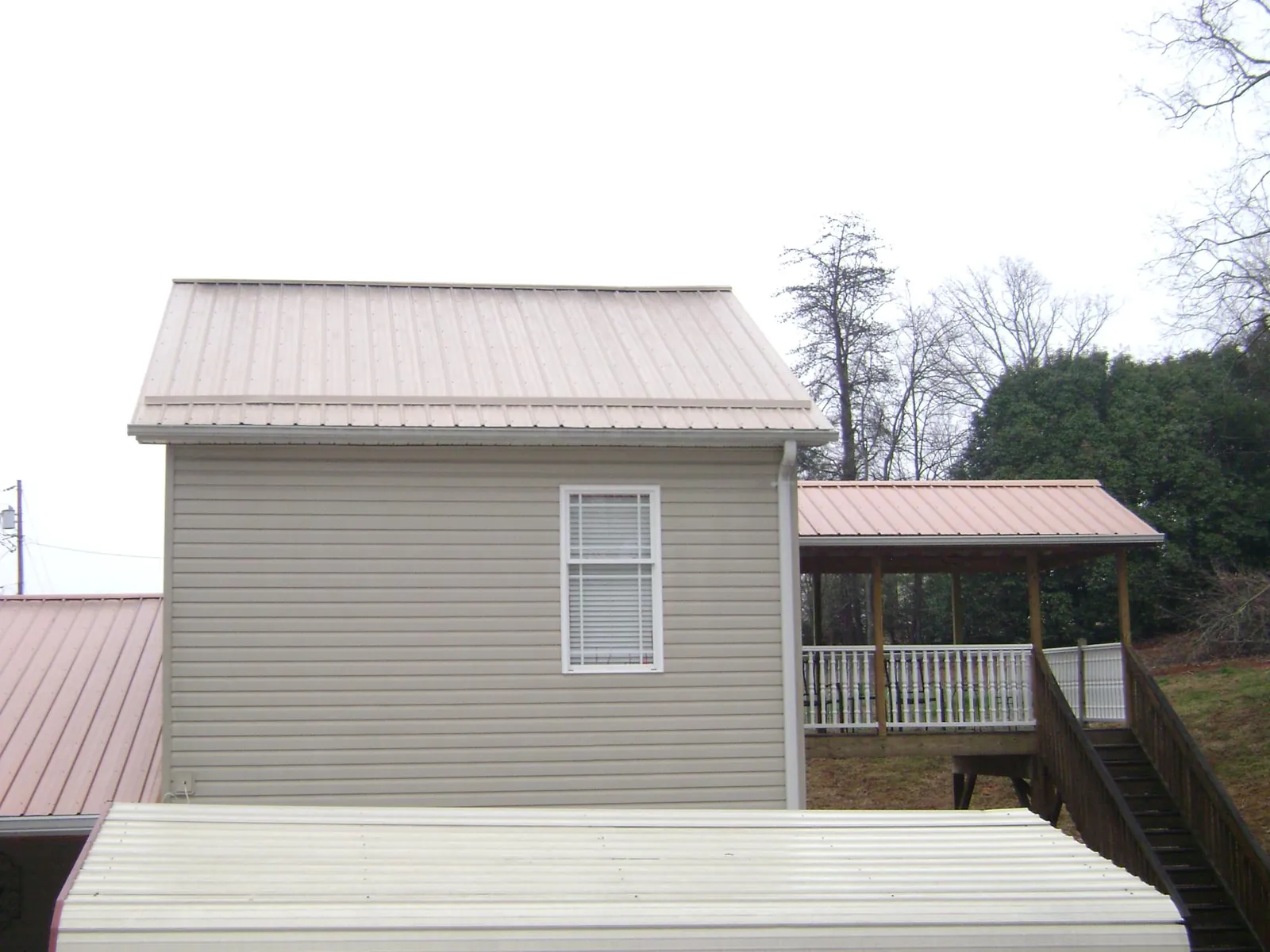 Tan metal roofs on a two story addition and attached porch, from a Roof Replacement job in Mound